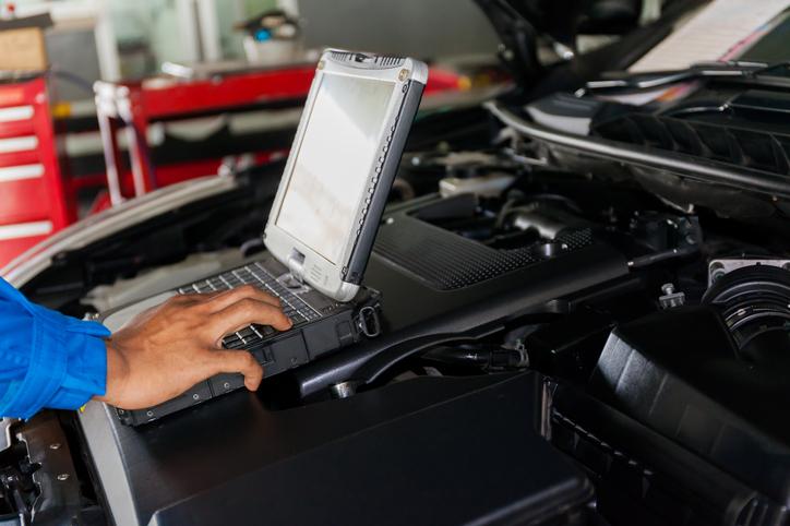 Image rapprochée d’un mécanicien-réparateur d’automobile faisant un diagnostic des éléments électroniques d’un véhicule.