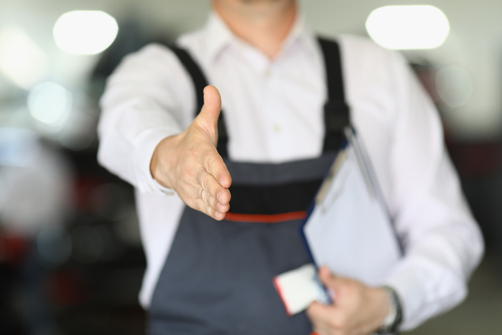 Étudiant en école mécanique qui tends la main pour saluer un client