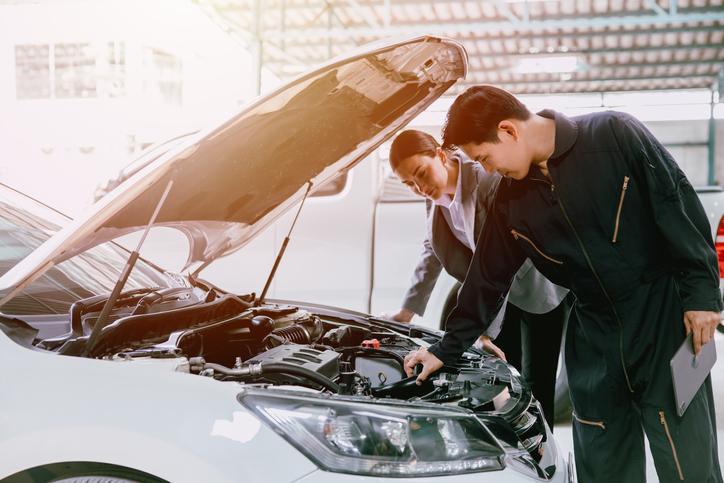 Étudiant en formation mécanique automobile qui travaille avec un client