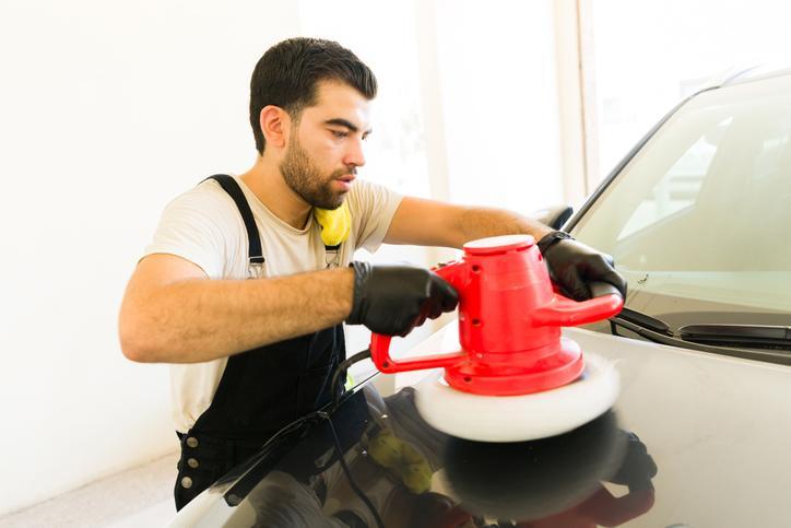 Étudiant en formation en esthétique automobile qui travaille sur la surface extérieure d’un véhicule