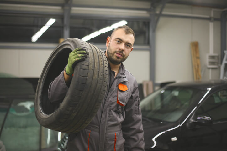 Étudiants en formation mécanique automobile qui porte un pneu en atelier