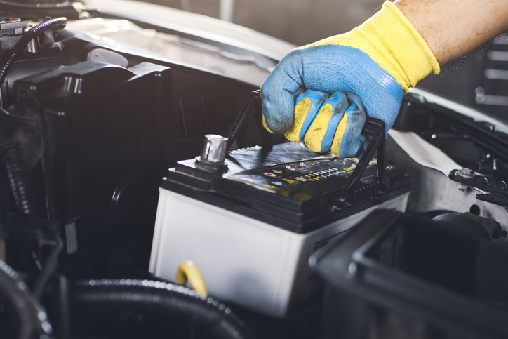 Image d'un mécanicien inspectant une batterie dans un atelier, prêt à tester pour déceler une fuite de courant.