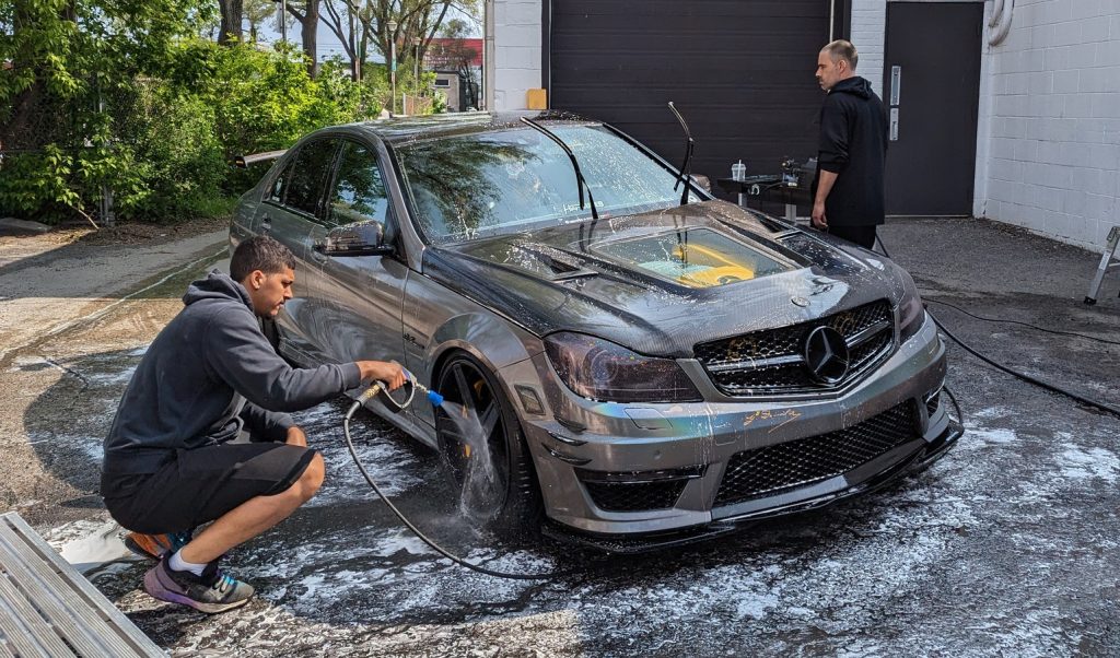 Étudiants en mécanique automobile lavant une Mercedes dans le cadre d’une action caritative.