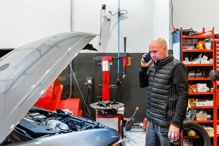 Un conseiller technique travaillant dans l’industrie automobile, au téléphone avec un client.