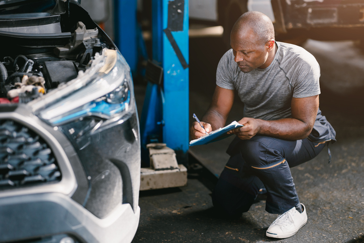 Estimateur expert en dommages automobiles en train d’inspecter un véhicule.